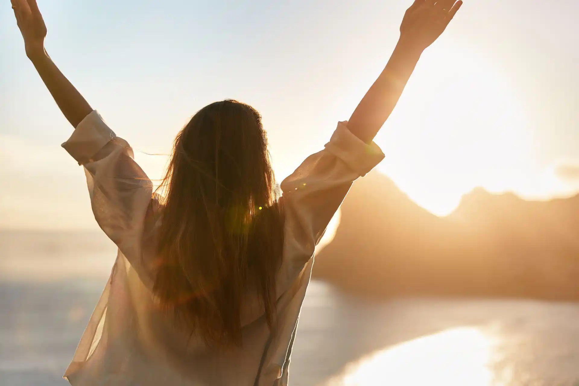Frau streckt die Arme in die Höhe und fühlt Freude