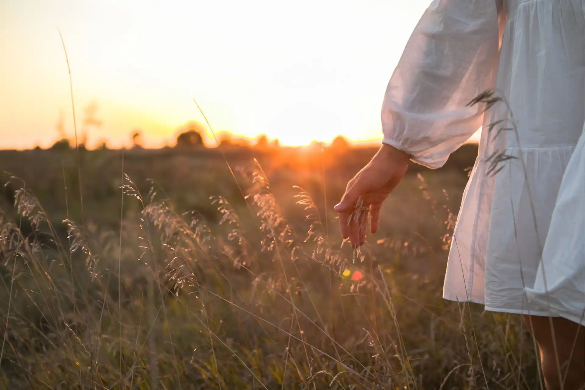 Frau streicht mit Hand durch Gräser in Kontakt mit sich